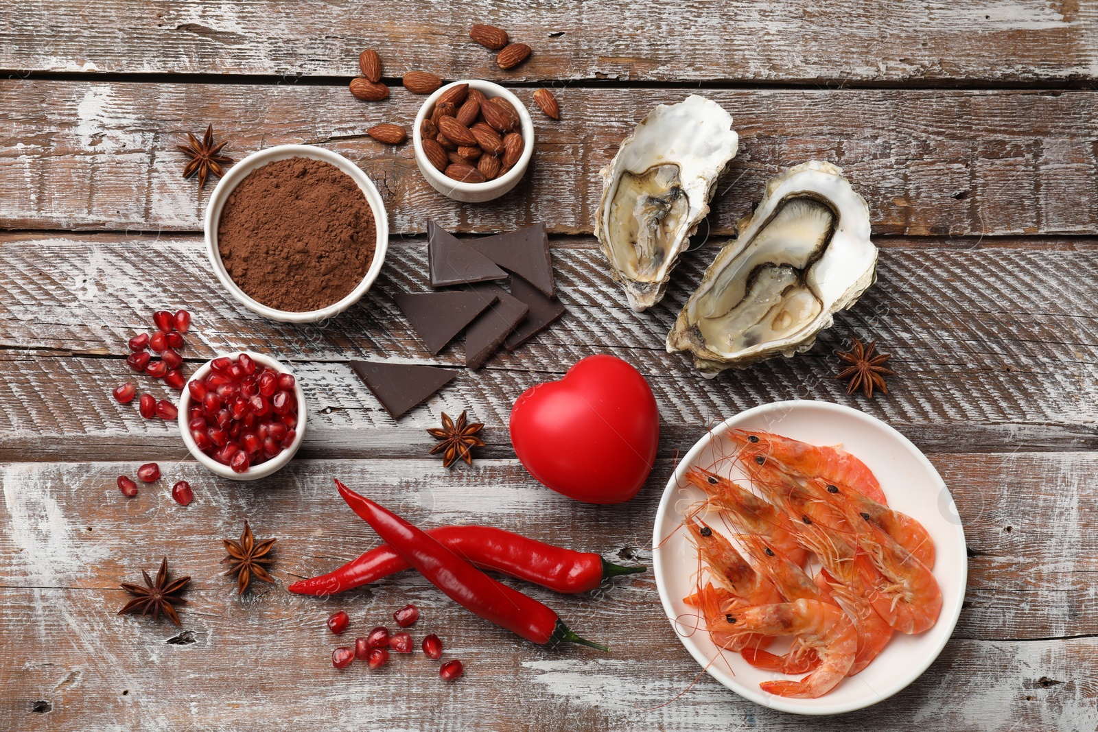 Photo of Natural aphrodisiac. Different food products and heart model on wooden table, flat lay