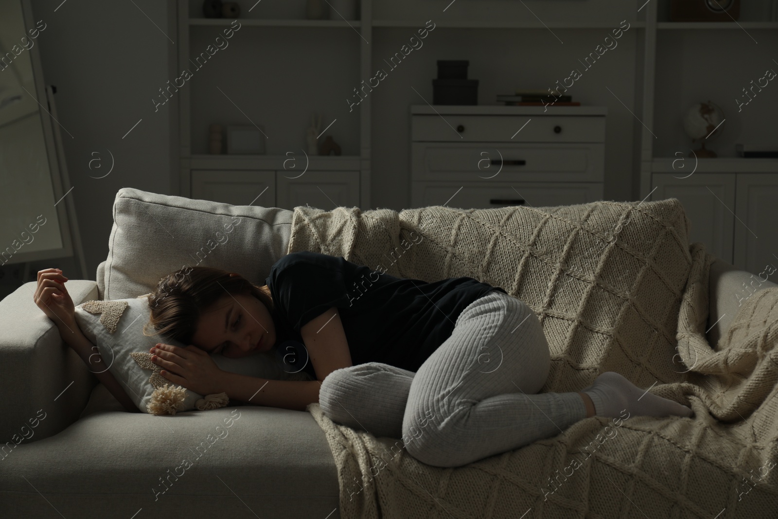 Photo of Sad young woman lying on sofa at home