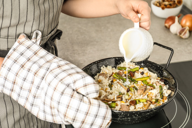 Photo of Woman cooking delicious risotto, closeup. Tasty recipe