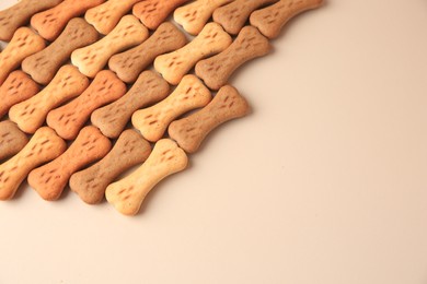 Bone shaped dog cookies on beige background, space for text