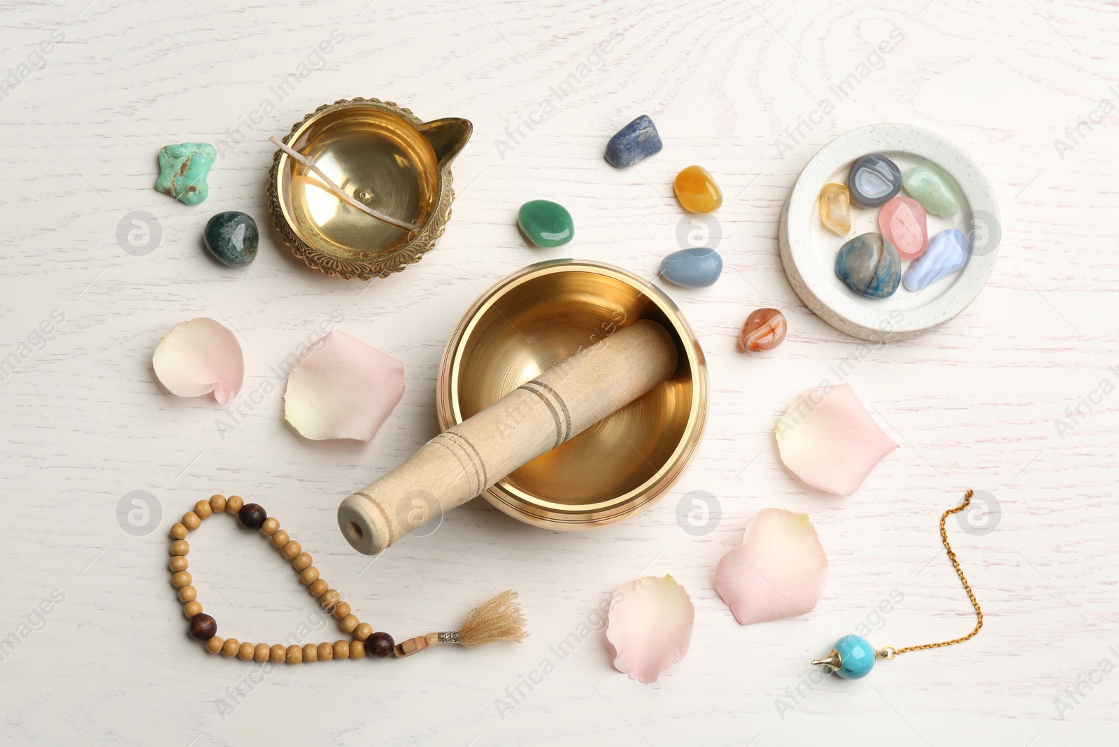 Photo of Flat lay composition with golden singing bowl on white wooden table. Sound healing