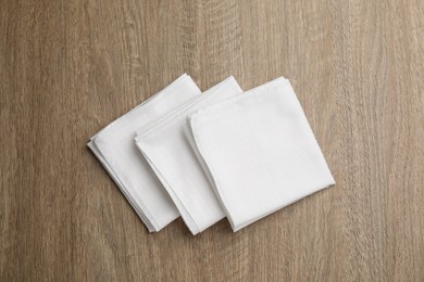 Photo of Stylish white handkerchiefs on wooden table, flat lay