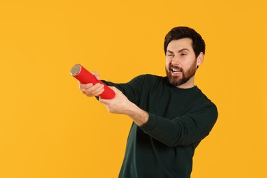 Handsome man with party popper on yellow background