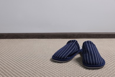 Pair of stylish slippers on carpet against light grey background, space for text