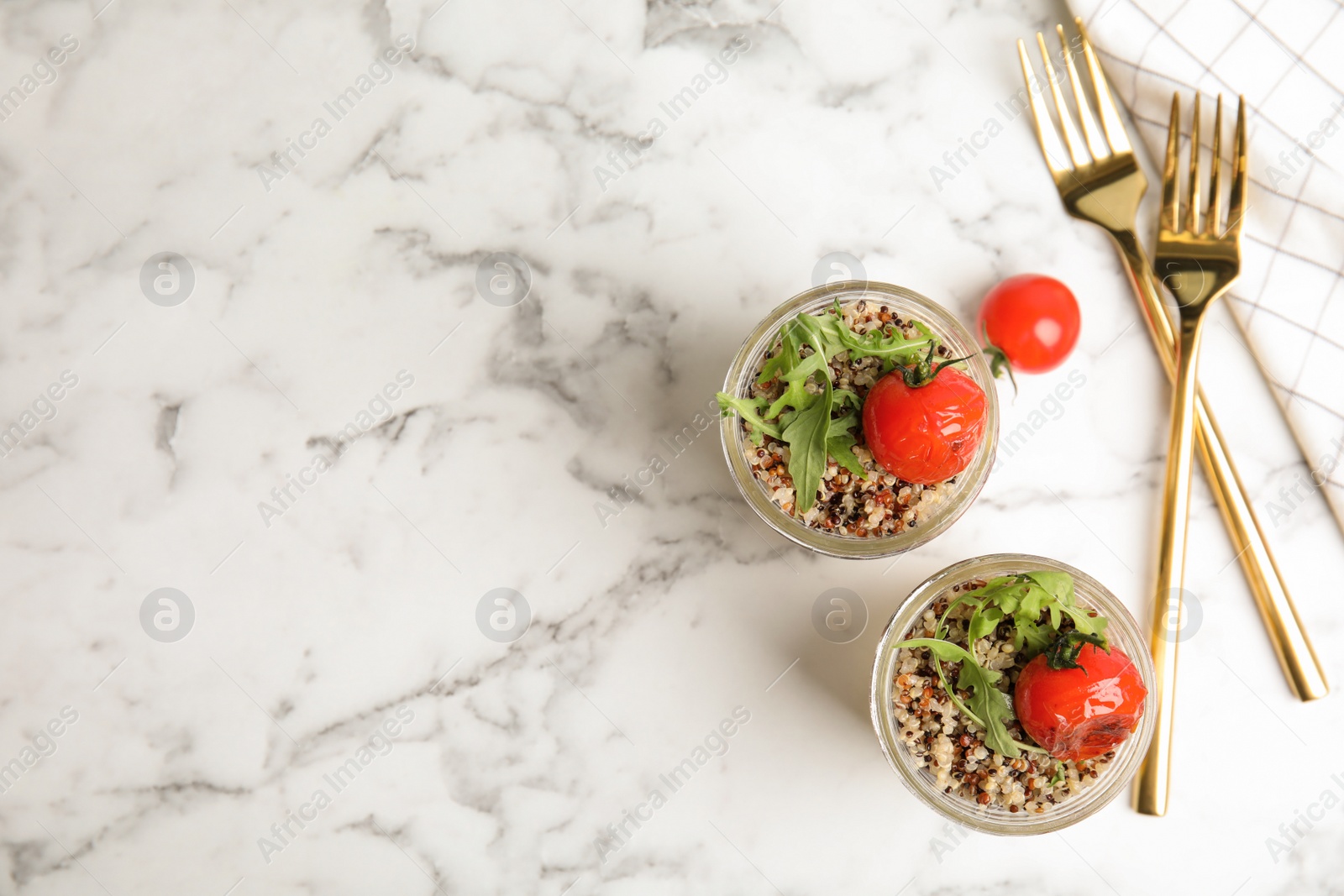 Photo of Healthy quinoa salad with vegetables in jars and forks on table, top view. Space for text