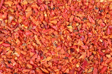 Photo of Aromatic spice. Red chili pepper flakes as background, top view