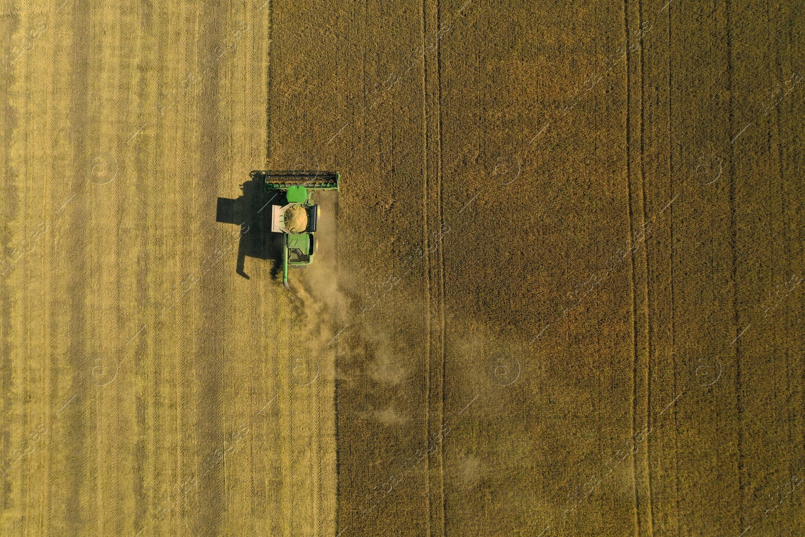 Photo of Beautiful aerial view of modern combine harvester working in field on sunny day, space for text. Agriculture industry
