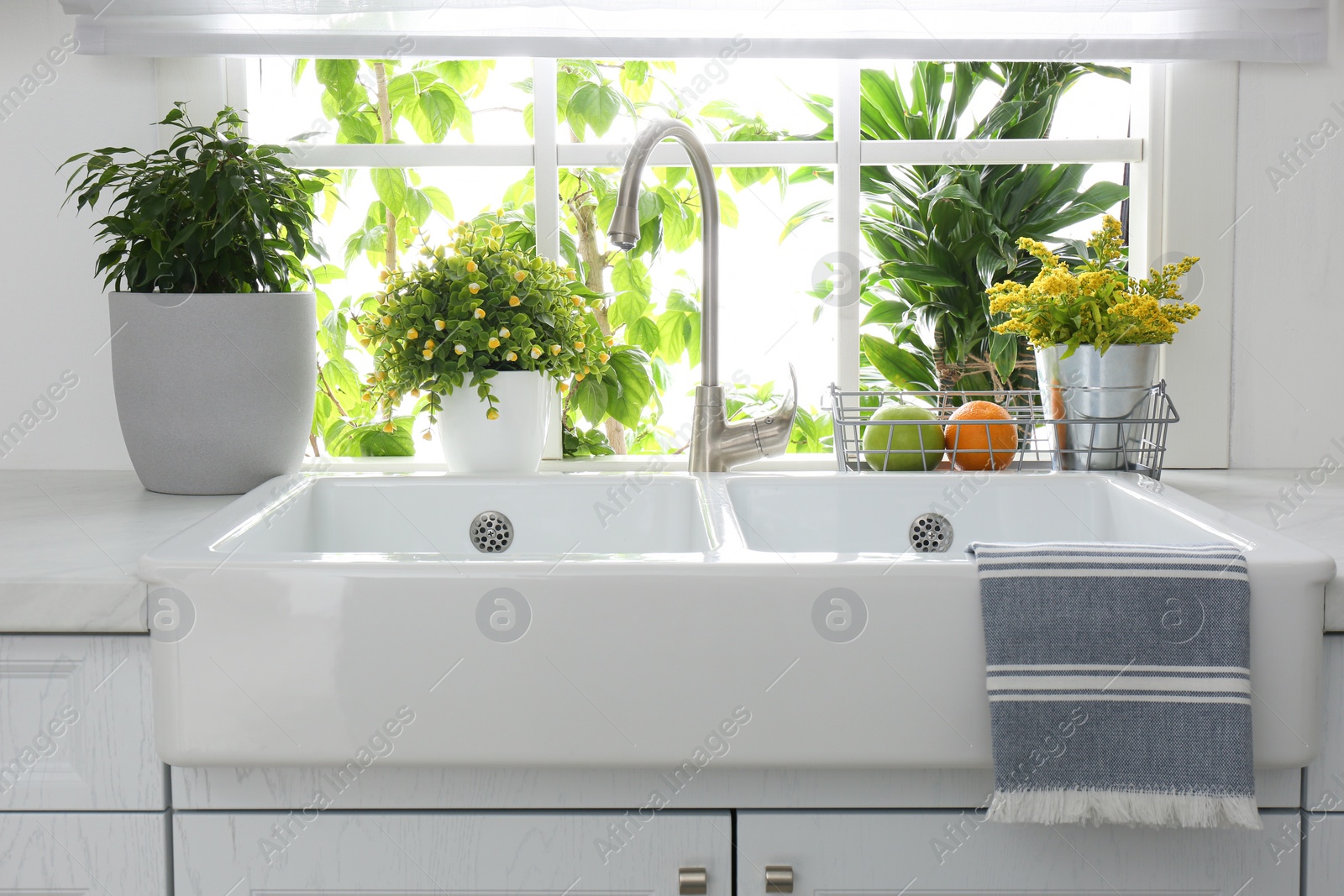 Photo of Beautiful white sink near window in modern kitchen