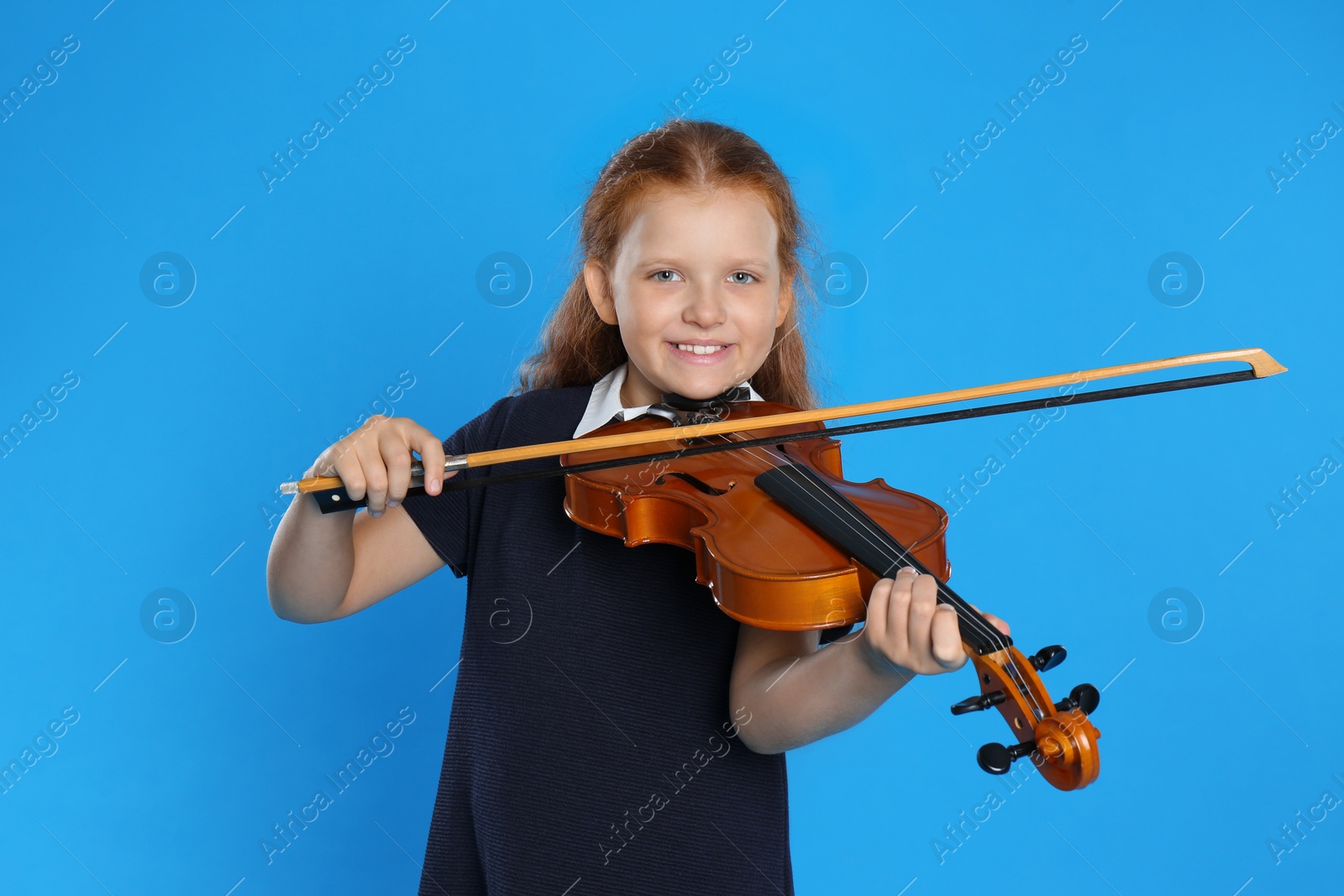 Photo of Preteen girl playing violin on light blue background