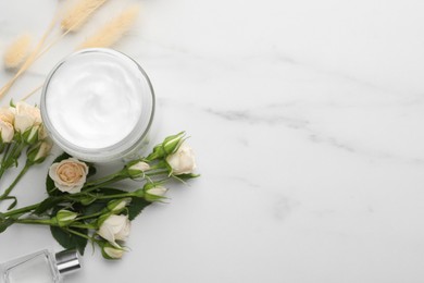 Photo of Jar of hand cream and roses on white marble table, flat lay. Space for text