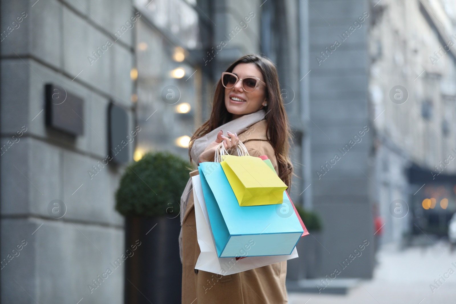 Photo of Beautiful young woman with shopping bags on city street