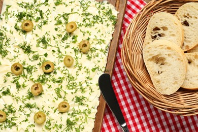 Photo of Fresh butter board with cut olives, bread and knife on table, flat lay