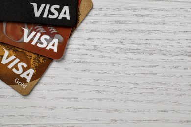 Photo of MYKOLAIV, UKRAINE - FEBRUARY 22, 2022: Visa credit cards on white wooden table, flat lay. Space for text