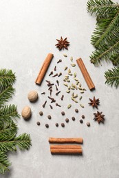Christmas tree made of different spices and fir branches on light gray textured table, flat lay
