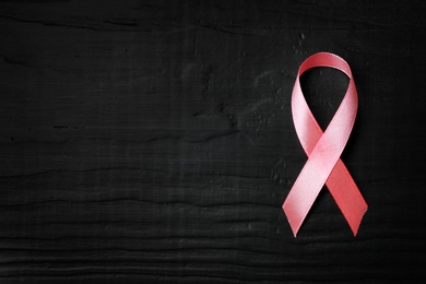 Photo of Pink ribbon on wooden background, top view with space for text. Breast cancer concept