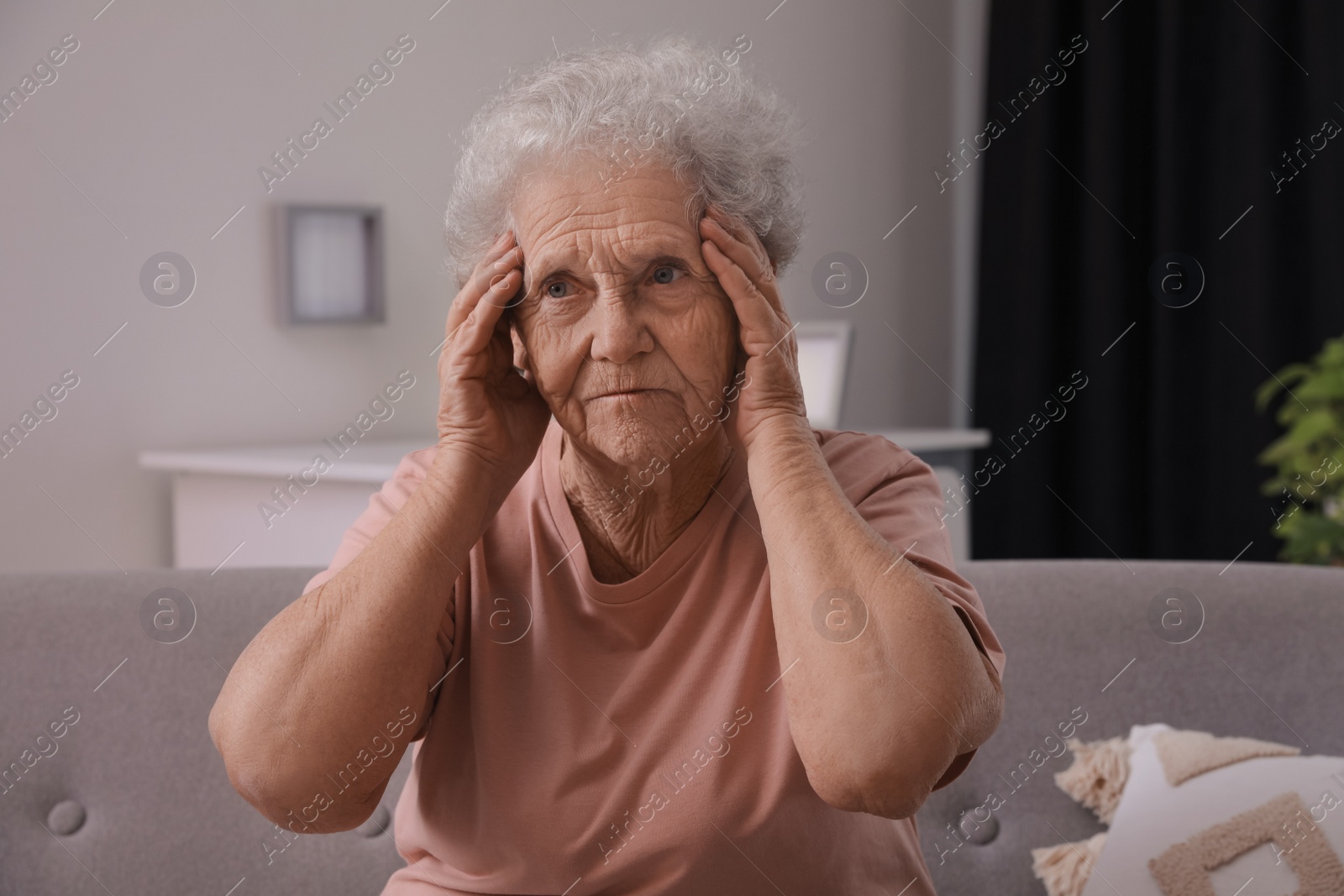 Photo of Senior woman with headache sitting on sofa at home