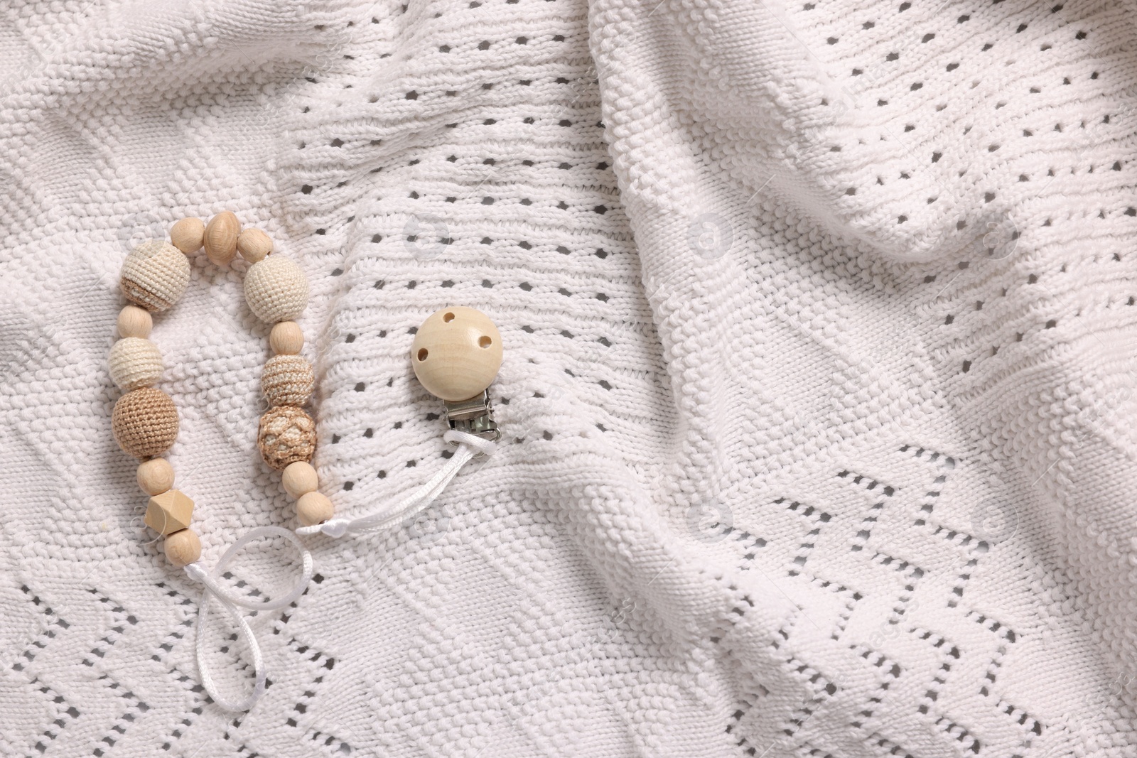 Photo of Baby accessory. Pacifier clip on white knitted fabric, top view. Space for text