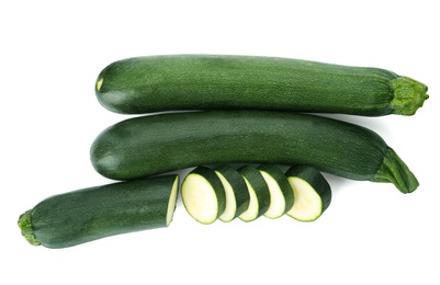 Photo of Cut and whole green ripe zucchini isolated on white, top view