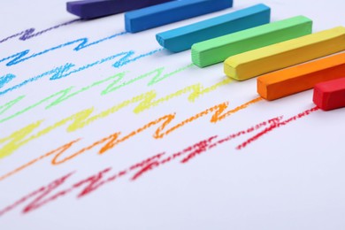 Photo of Colorful pastel chalks and scribbles on white background, closeup. Drawing materials