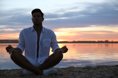 Man near river at sunset, space for text. Nature healing power