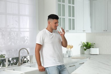 Photo of Man drinking tap water from glass in kitchen