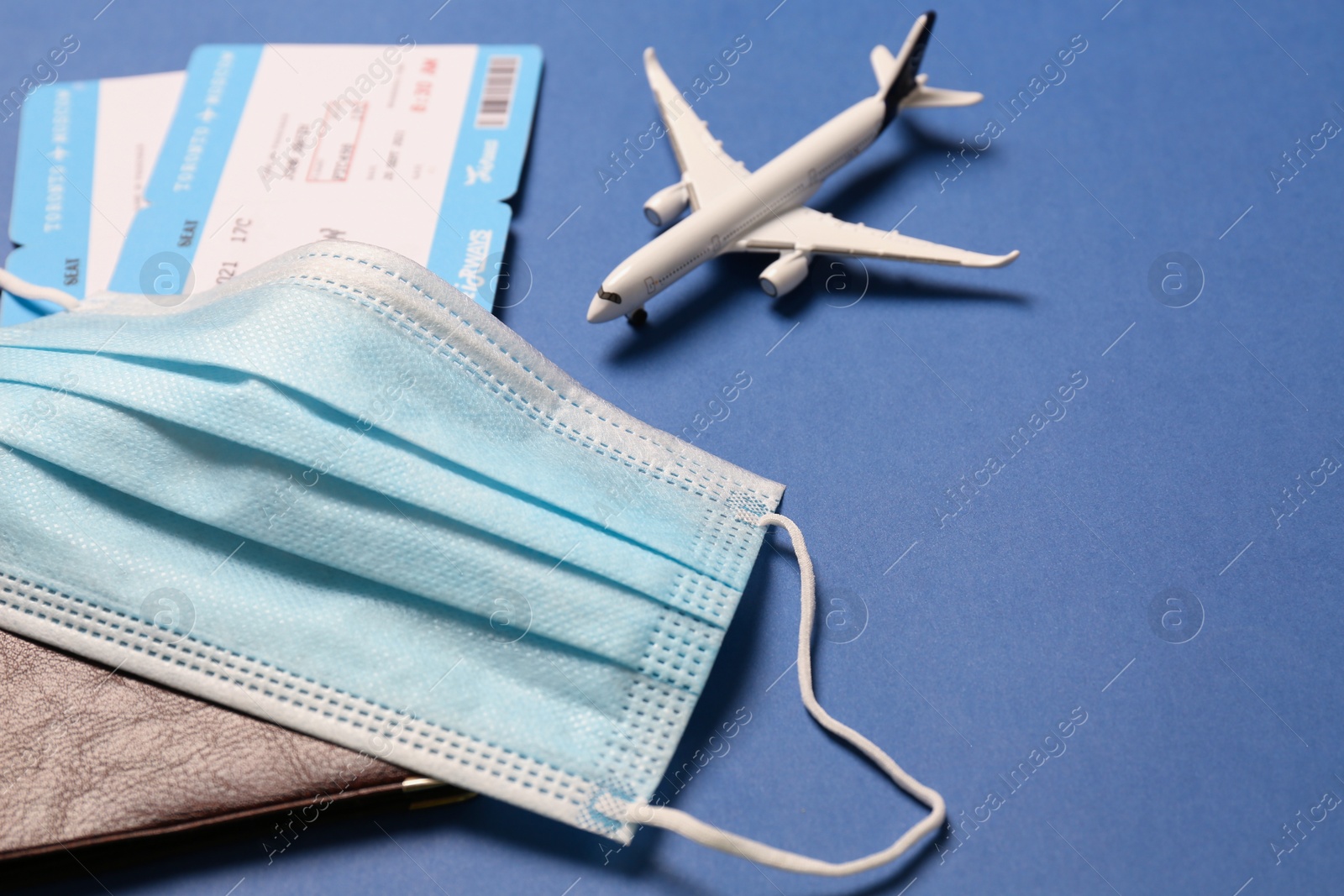 Photo of Composition with passport and protective mask on blue background, closeup. Travel during quarantine