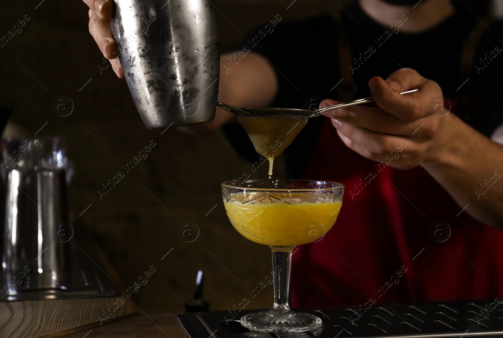 Photo of Bartender preparing fresh alcoholic cocktail at bar counter, closeup