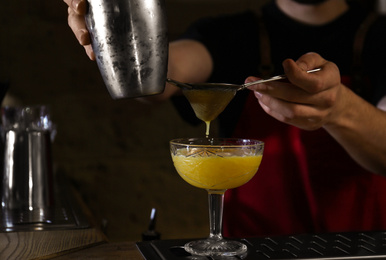 Photo of Bartender preparing fresh alcoholic cocktail at bar counter, closeup