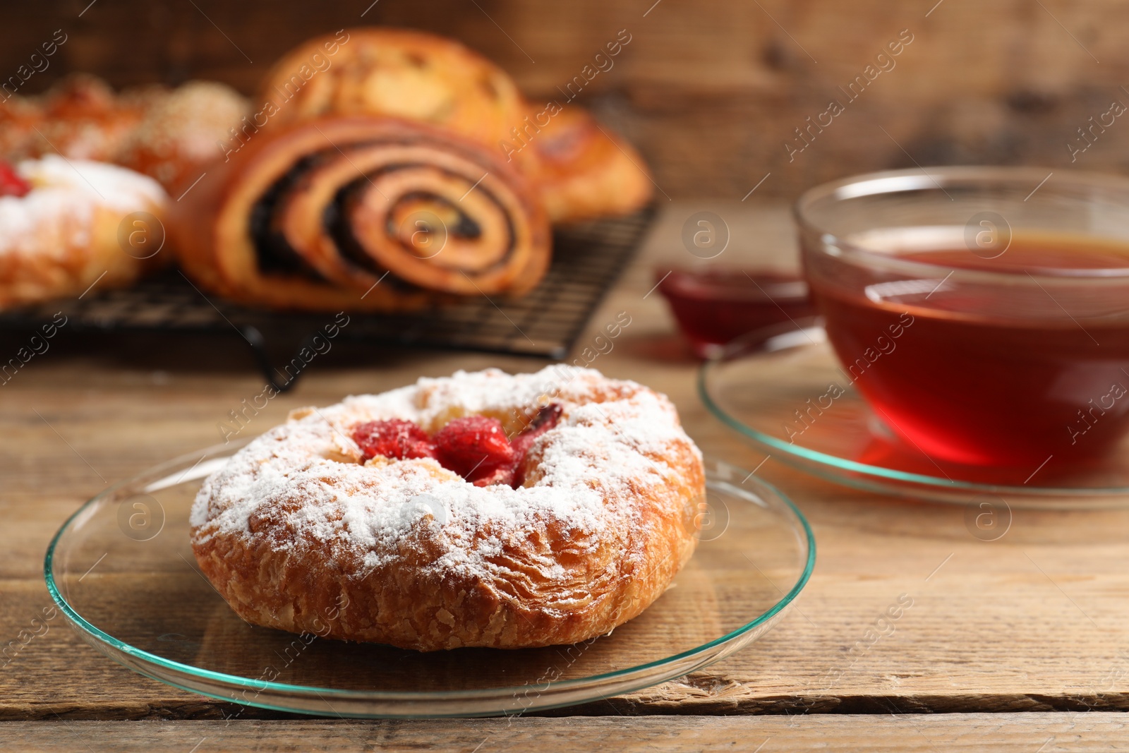 Photo of Danish bun with strawberry and other pastries on wooden table