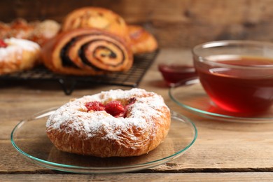 Danish bun with strawberry and other pastries on wooden table