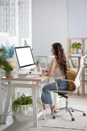 Photo of Young woman working on computer at table in room