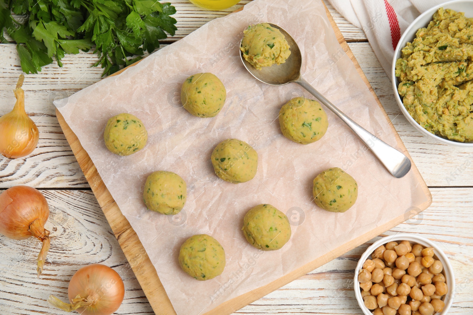 Photo of Raw falafel balls and ingredients on white wooden table, flat lay