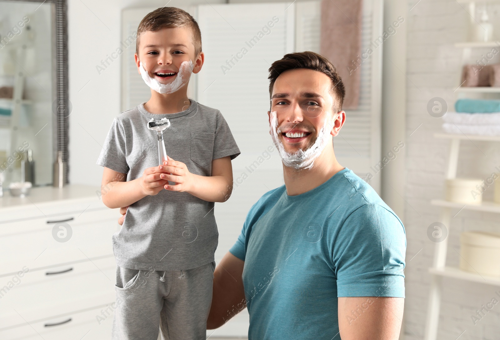 Photo of Dad and his little son with shaving foam on faces in bathroom