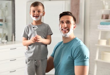 Dad and his little son with shaving foam on faces in bathroom