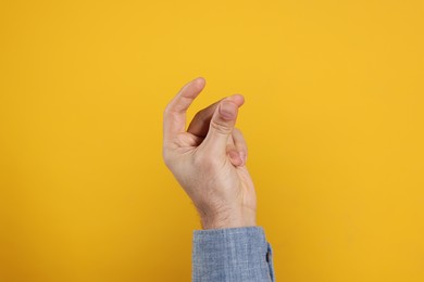 Photo of Man snapping fingers on yellow background, closeup of hand
