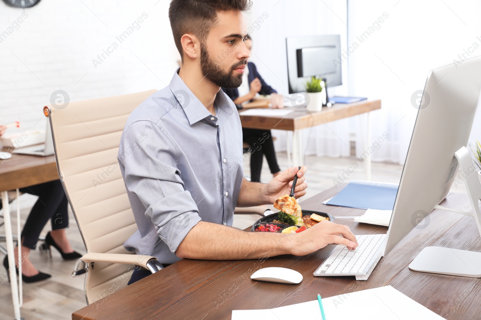 Photo of Office employee having lunch at workplace. Food delivery