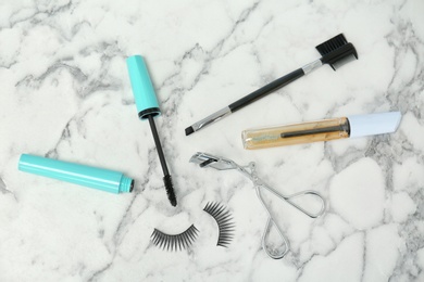 Flat lay composition with false eyelashes, cosmetic products and tools on light background