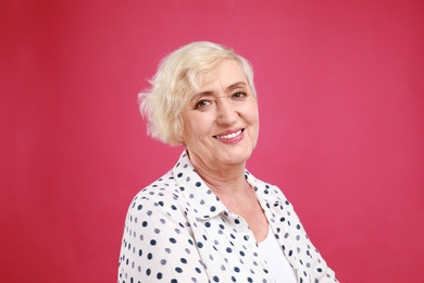 Senior woman in casual outfit on crimson background