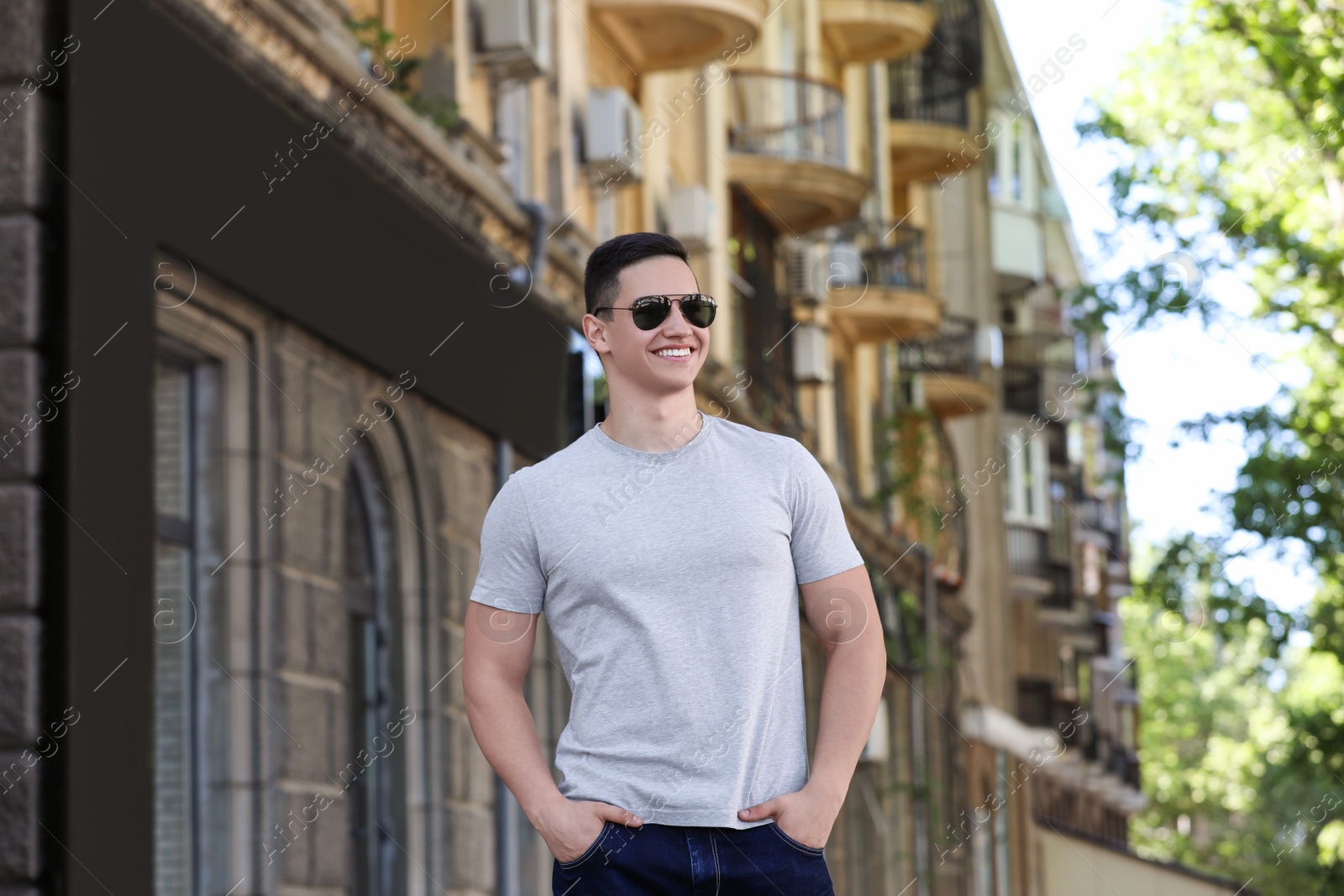 Photo of Young man in grey t-shirt outdoors. Mockup for design