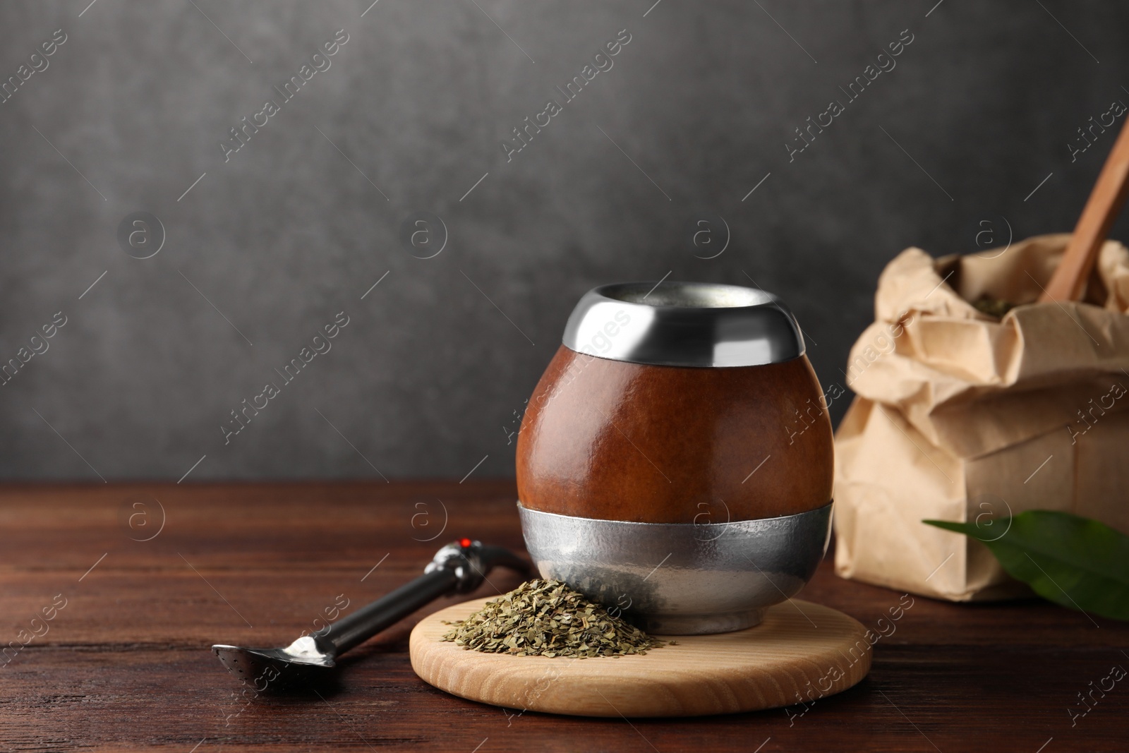 Photo of Calabash with mate tea and bombilla on wooden table. Space for text