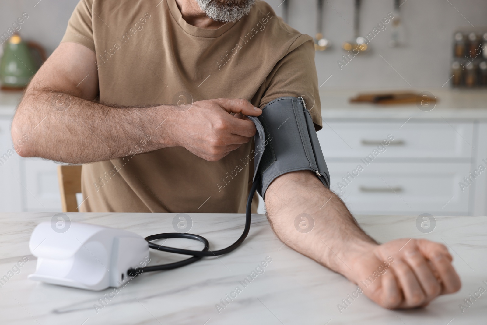 Photo of Man measuring blood pressure at table indoors, closeup