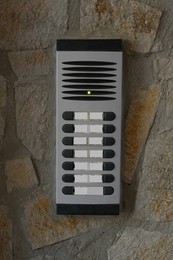 Modern intercom on concrete wall with stone fragments. Security system