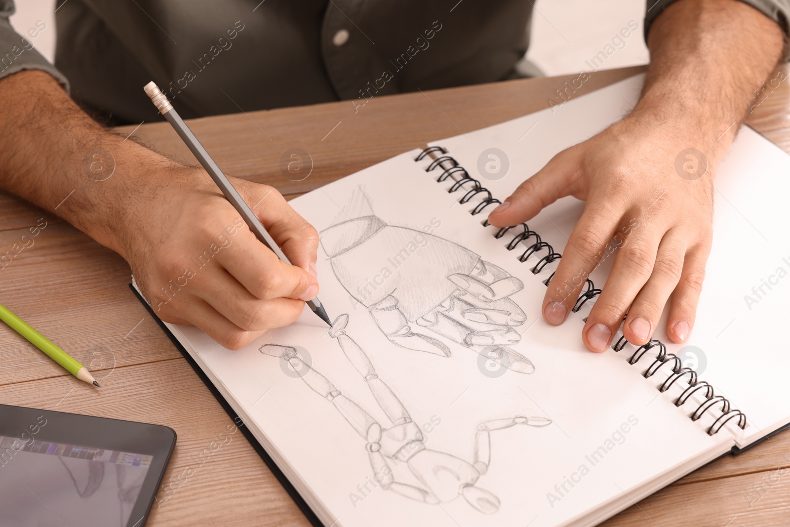 Photo of Man drawing in sketchbook with pencil at wooden table, closeup