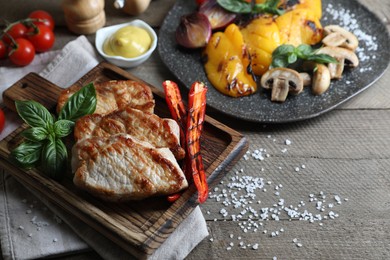 Photo of Delicious grilled meat and vegetables served on wooden table