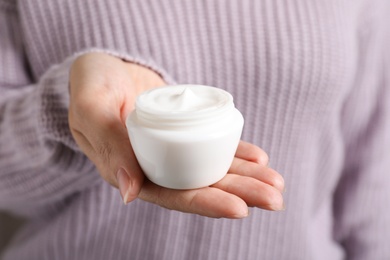 Photo of Woman holding jar of moisturizing cream, closeup. Winter skin care cosmetic