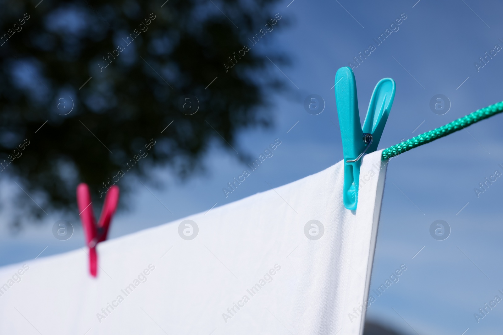 Photo of Laundry with clothes pins on line outdoors, closeup