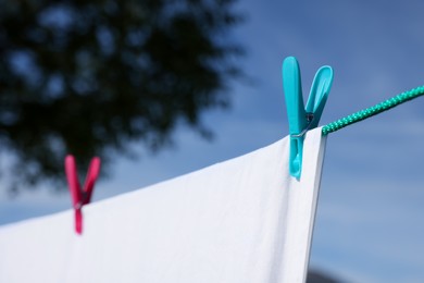 Photo of Laundry with clothes pins on line outdoors, closeup