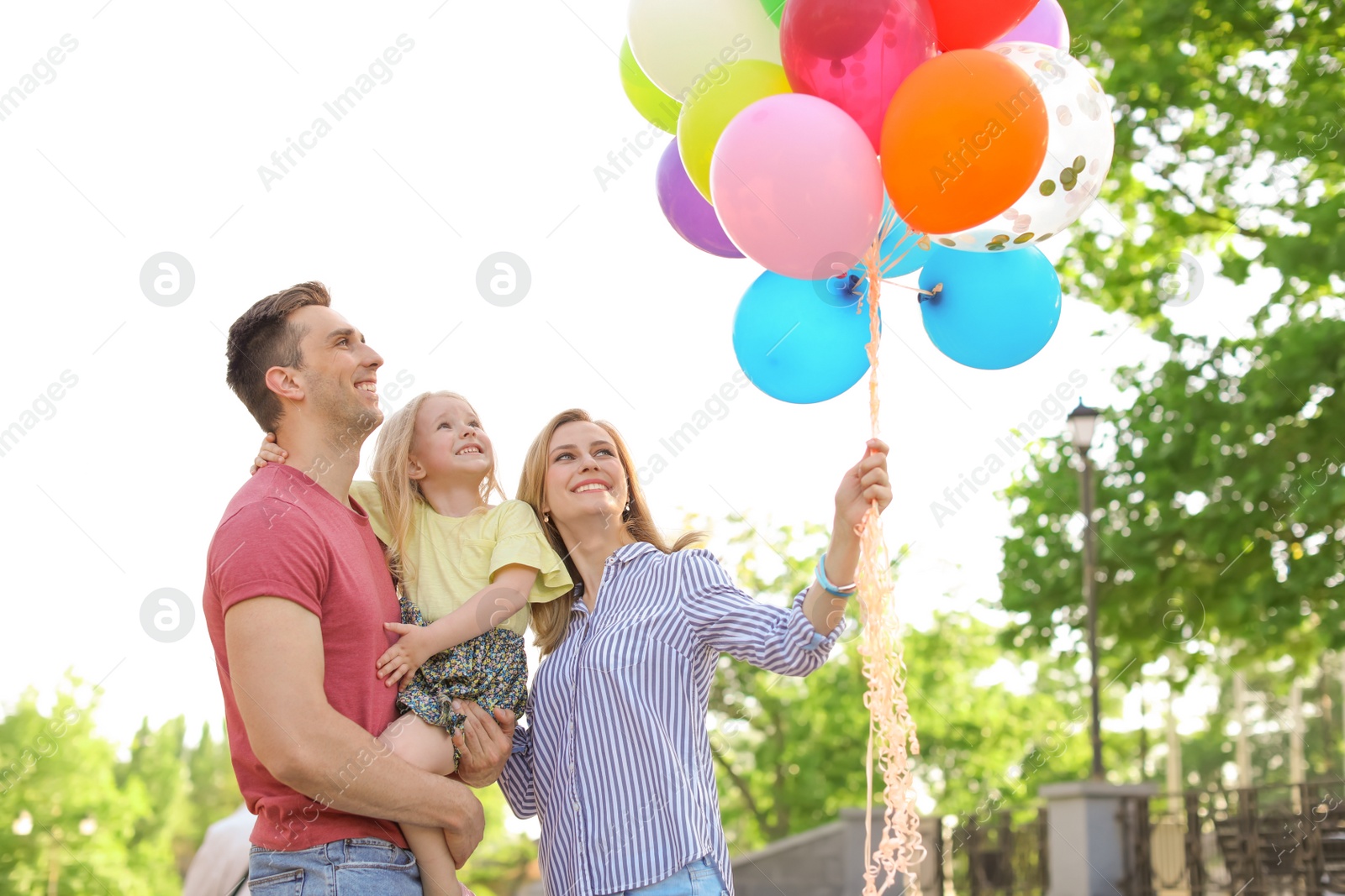 Photo of Happy family with colorful balloons outdoors on sunny day