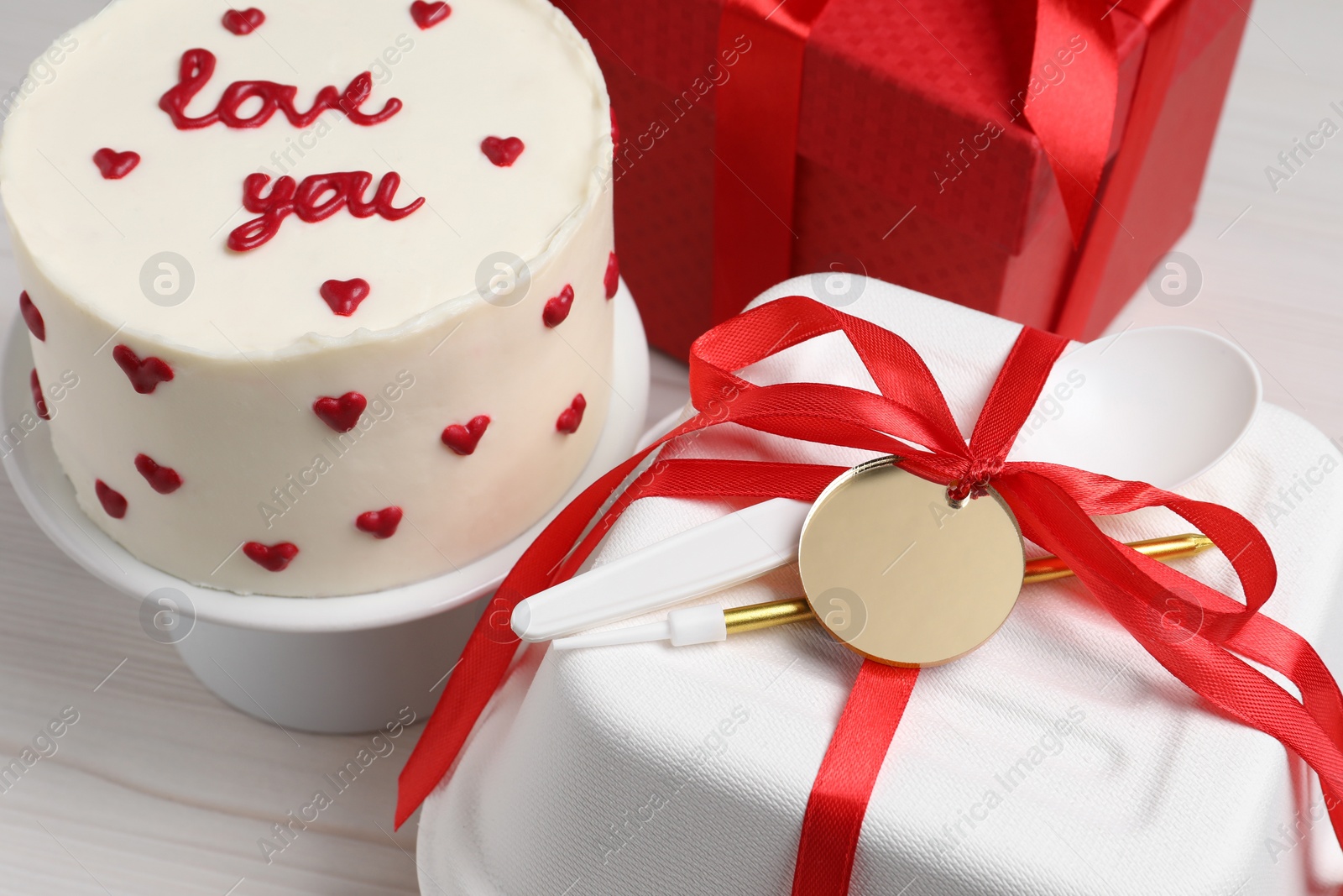 Photo of Bento cake with text Love You, gift box and takeaway packaging on white wooden table. St. Valentine's day surprise