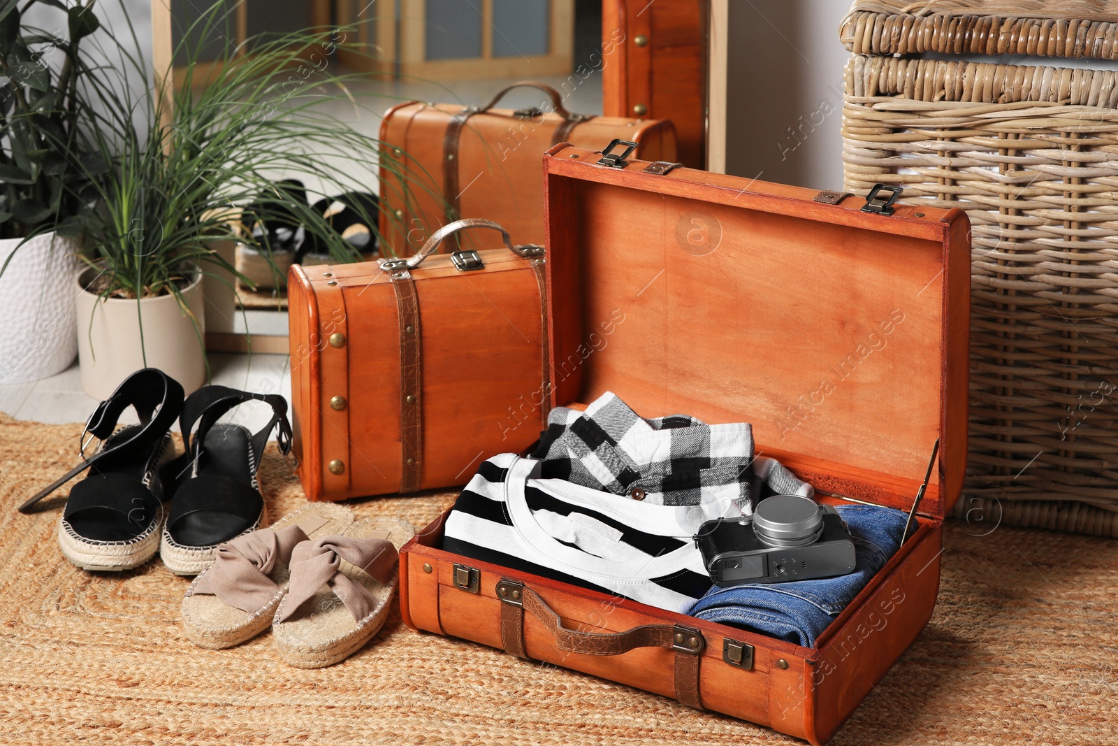 Photo of Open suitcase with folded clothes, accessories and shoes on carpet indoors